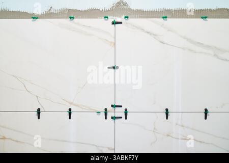 Marble tiles in the bathroom align large ceramic tiles on the wall using plastic clips and partitions. With the ability to copy. High quality photo Stock Photo