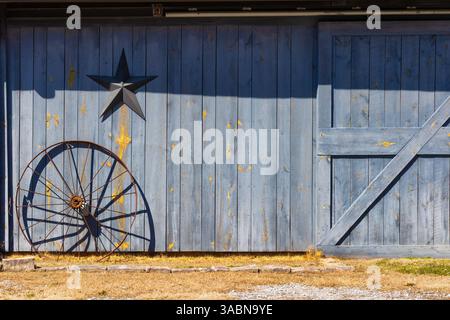 Close up of an outdoors side wall of a barn with a iron wheel and metal star in rural Tennessee, USA Stock Photo