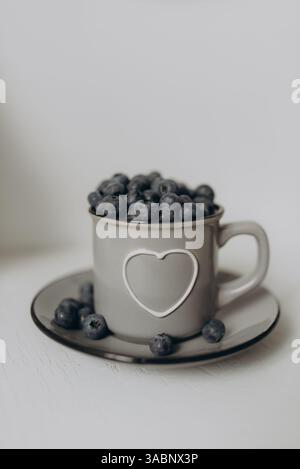 A cup filled with fresh blueberries placed on a clean white background Stock Photo