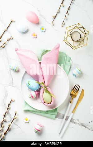 Spring table setting - White plate, golden cutlery and colored easter eggs. Top view with copy space. Stock Photo