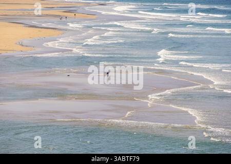 Aerial view at people walking among the breaking waves on a sandy beach on a beautiful summer day, Crozon peninsula, Bretagne, France, Europe Stock Photo