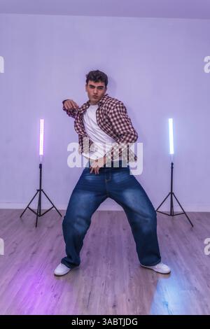 Young man dancing in a studio illuminated by led lights, showcasing energetic moves and expressing passion through dance Stock Photo