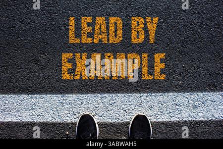 Lead by example message written on asphalt road. Conceptual lead by example symbol. Copy space. Stock Photo