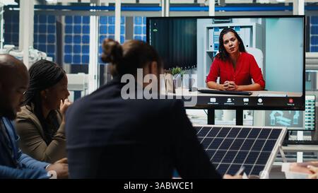 Factory engineers doing online videocall to refine designs for increased energy output using data. Photovoltaics plant specialists design solar cell prototypes in teleconference meeting, camera B Stock Photo