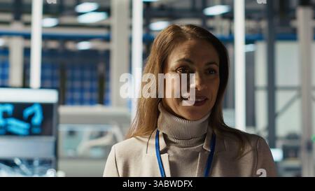 Portrait of smiling scientist in factory using tablet to check PV materials parameters, improving solar panels. Happy researcher develops efficient sustainable energy solutions using device, camera B Stock Photo