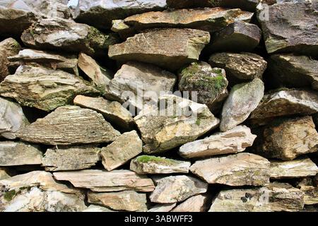 Natural stone wall with irregular rocks and moss texture. Ideal for eco-building, rustic architecture, or natural background use. Stock Photo