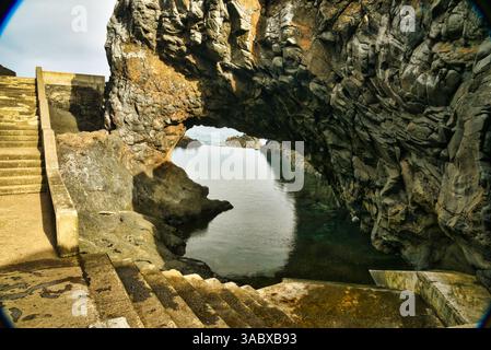 Steps leading down to Poças das Lesmas, a coastal natural swimming pool within arching lava rock outcroppings in Seixal, Madeira Island, Portugal Stock Photo