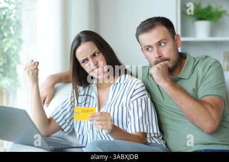 Angry couple having problems buying online with credit card and laptop Stock Photo