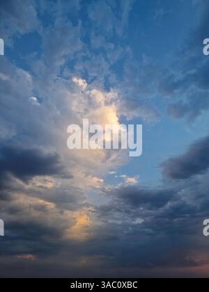 Sky view filled with dramatic clouds during sunset after the storm. Sunlight peeks through, creating a stunning and atmospheric cloudscape scene with Stock Photo