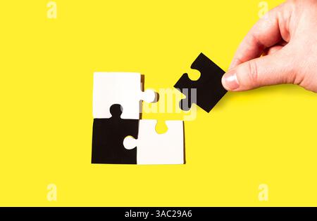 Hand trying to finish puzzle connecting the last piece of puzzle. Business, team work and completing hard task concept Stock Photo