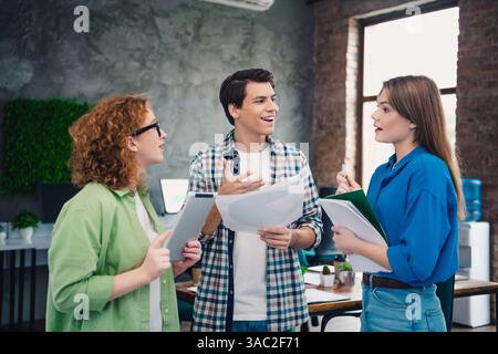 A group of young professionals having an engaging discussion in a modern coworking space, collaborating on tasks Stock Photo