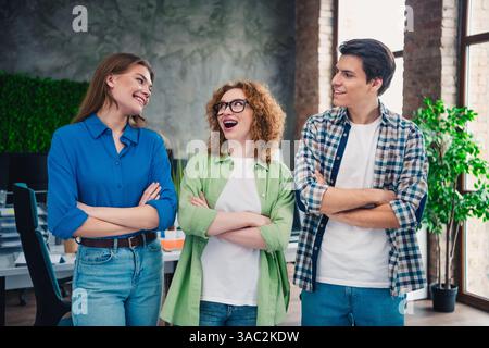 Three young professionals in a modern casual office environment collaborating and enjoying friendly conversation fostering teamwork Stock Photo