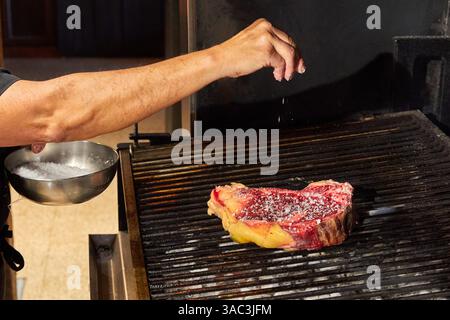 Grill chef putting salt on a chop, restaurant grill, Gipuzkoa, Basque Country, Spain Stock Photo