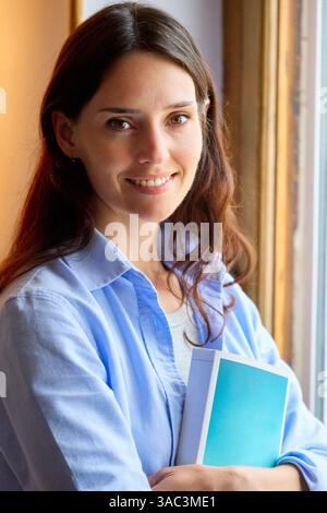 woman looking at the camera with a book in her arms Stock Photo
