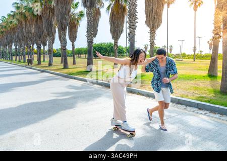 Young diverse couple with skateboard and longboard having fun outdoors. Stock Photo
