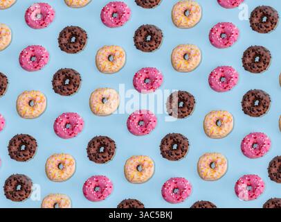 Sweet colorful sugar glazed donuts on light blue background. Three tasty doughnuts - chocolate, vanilla, strawberry pink, copy space Stock Photo