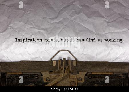 Inspiration exists but it has find us working close up of a phrase being typed and centered on a sheet of paper on an old vintage mechanical typewrite Stock Photo