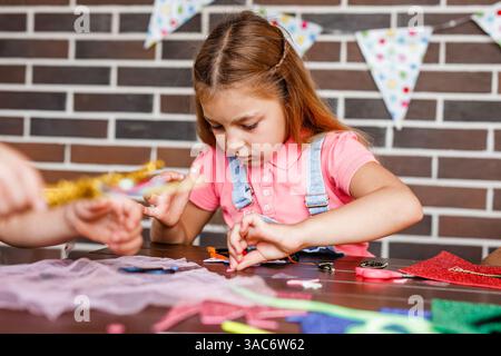 Cute preschooler girl makes art at a summer outdoor party. Stock Photo