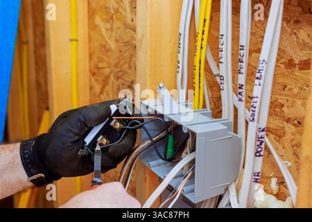 An electrician is connecting wires to switch light in junction box while preparing for electrical service installation Stock Photo