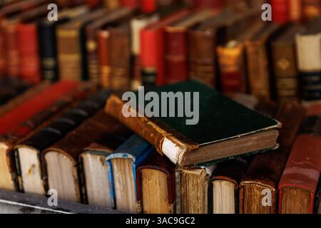 A stack of books with a green book on top. The books are old and worn Stock Photo