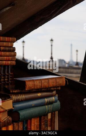 Bookshop on the Seine River embankment. Eiffel Tower in the background. A stack of books is piled on top of each other. Stock Photo