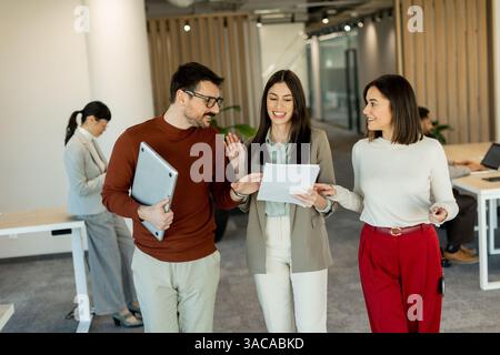 A group of professionals engages in lively discussions while reviewing documents, embodying teamwork and creativity in a bright, contemporary workspac Stock Photo
