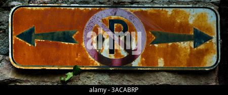 Details of an old and heavily rusted red no-parking sign with black arrows in both directions, X-Pan-format Stock Photo