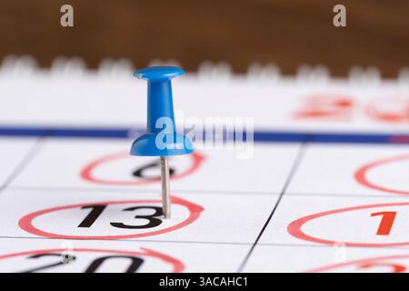 Calendar with blue push pin on wooden background, closeup Stock Photo