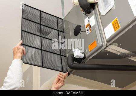Replacing dirty central air conditioning  air filter.  HVAC repair technician performing maintenance on home indoor heating and cooling system. Stock Photo