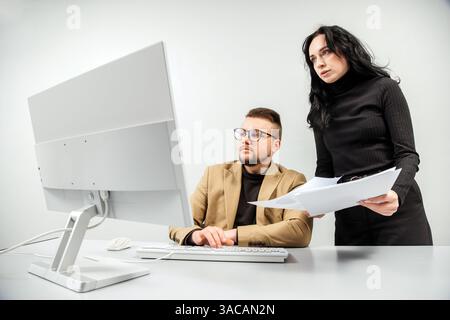 Two versatile business analysts discussing data management using a laptop. Concept consulting, training Stock Photo