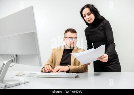 Two versatile business analysts discussing data management using a laptop. Concept consulting, training Stock Photo