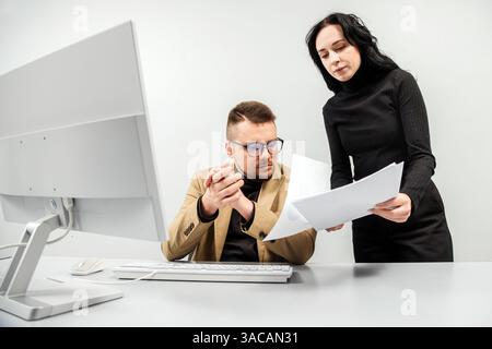 Two versatile business analysts discussing data management using a laptop. Concept consulting, training Stock Photo