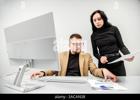 Two versatile business analysts discussing data management using a laptop. Concept consulting, training Stock Photo