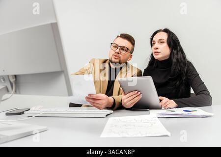 Two members of a finance team working together on a project during a brainstorming meeting. Concept collaborative teamwork, strategy planning Stock Photo