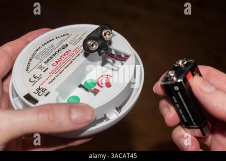 Photoelectric smoke alarm and Pairdeer Super Heavy Duty battery held in hands. Stock Photo