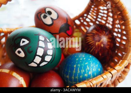 Easter eggs painted in different colors with painted laughing faces. Funny grimaces with eyes tongue and big white teeth. Scary face for Halloween. Em Stock Photo