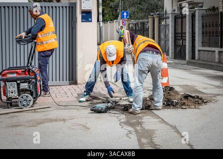 Utility workers on the street using special equipment. Plumbers prepares to fix the problem in the sewer. Repair work and maintenance outdoor street, Stock Photo