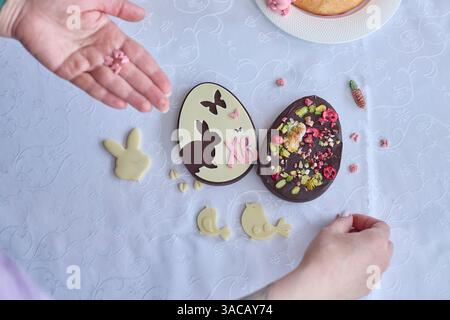 Craft a sweet Easter scene, depicting hands assembling chocolate eggs and cheerful baked figurines, invoking warmth and festive delicacy, perfect for Stock Photo