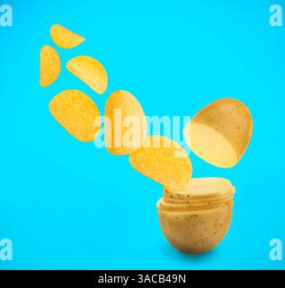 Raw potato slices transforming into crispy chips in air on light blue background Stock Photo