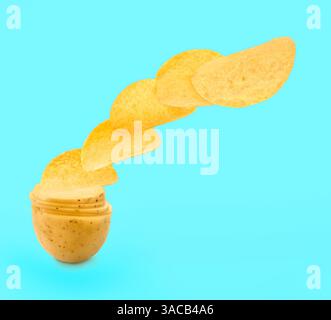 Raw potato slices transforming into crispy chips in air on turquoise background Stock Photo
