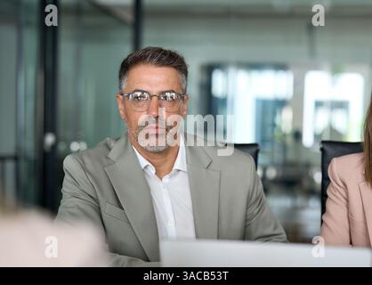 Serious older business man manager working at team office meeting table. Stock Photo