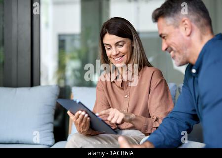 Two happy professional business executives talking using tablet in office. Stock Photo