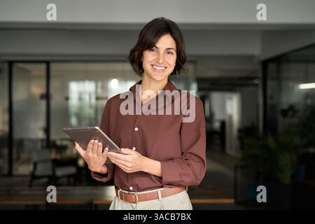 Happy professional female executive standing in office using tablet. Portrait Stock Photo