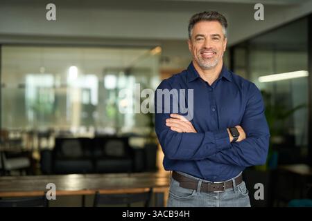 Smiling mature business man leader standing arms crossed in office. Portrait. Stock Photo