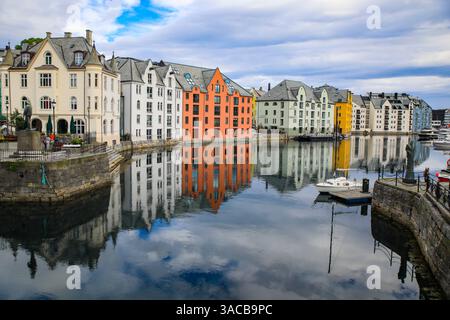 Alesund, Norway. Canal with colorful painted houses, boats, marina, sailor statue. Stock Photo