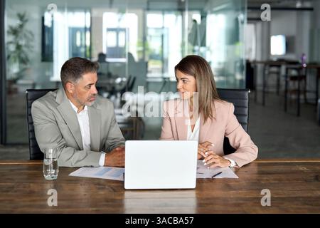 Two professional business executives working on laptop at office meeting. Stock Photo