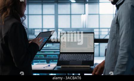 Programmers using AI technology on laptop and tablet in data center employing machine learning models. Devices used by artificial intelligence IT experts in server farm, camera A Stock Photo
