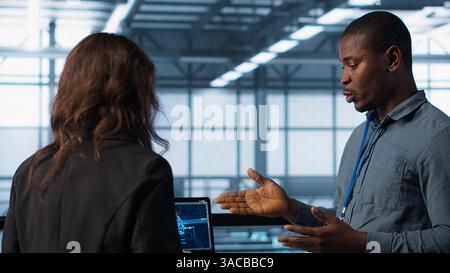 Team of engineers in data center with tablet integrating AI driven automation tools, doing maintenance. Teamworking colleagues in server room using artificial intelligence, camera A Stock Photo