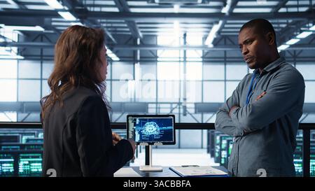 Team of engineers in data center with tablet integrating AI driven automation tools, doing maintenance. Teamworking colleagues in server room using artificial intelligence, camera B Stock Photo