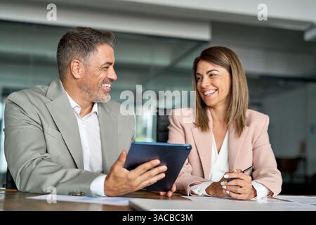 Two happy executives business people talking working on tablet in office. Stock Photo